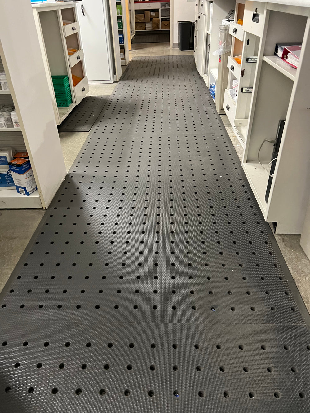 Long perforated mat fitted along a cabinet-lined workspace